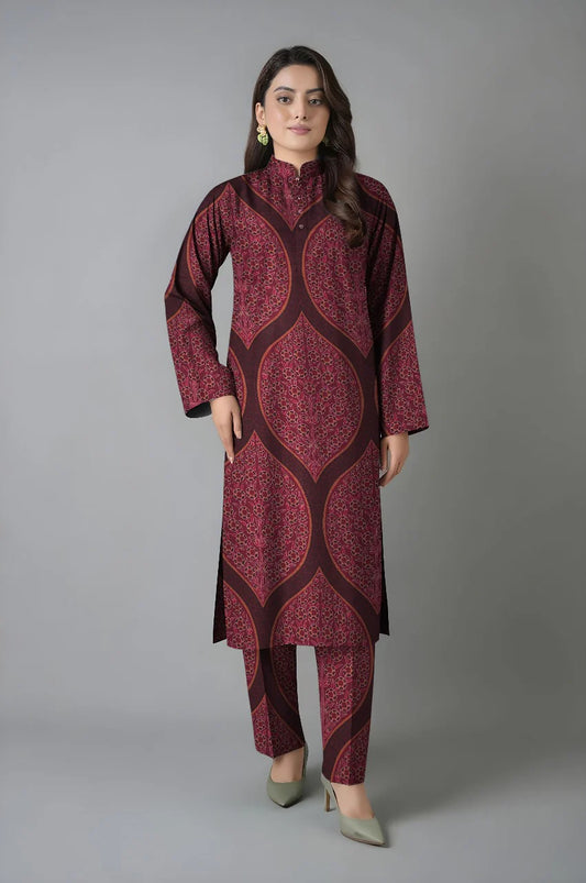 Woman wearing a maroon patterned kurta with pants against a gray background