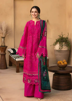 Woman in a bright pink traditional outfit with green accents standing in a room with decorative elements.
