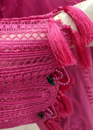 Close-up of a pink lace garment with tassels on a mannequin.